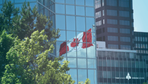 Canadian flag reflected in glass building.