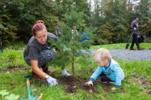 A mother and her young infant planting a tree.