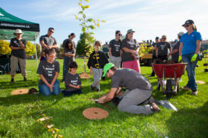 Man providing a tree planting demonstration to a group of people.