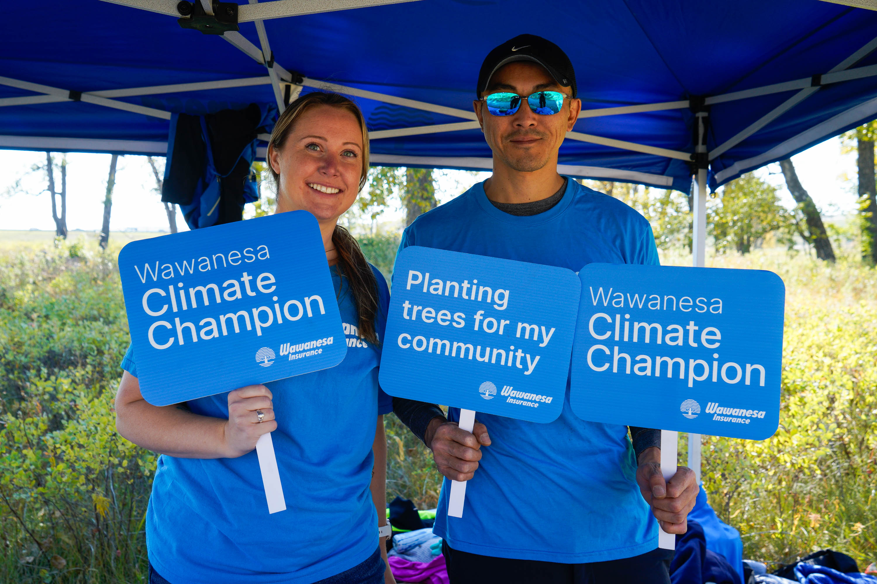 Two Wawanesa employees holding up Climate champion signs