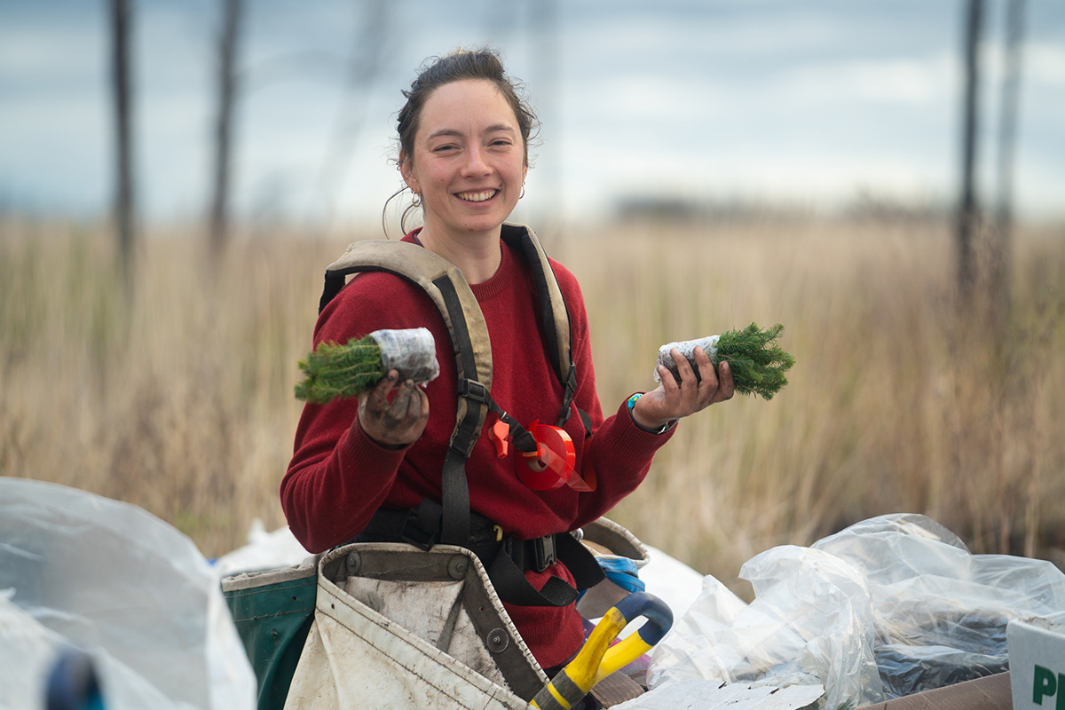 woman holding a seedling in each hand