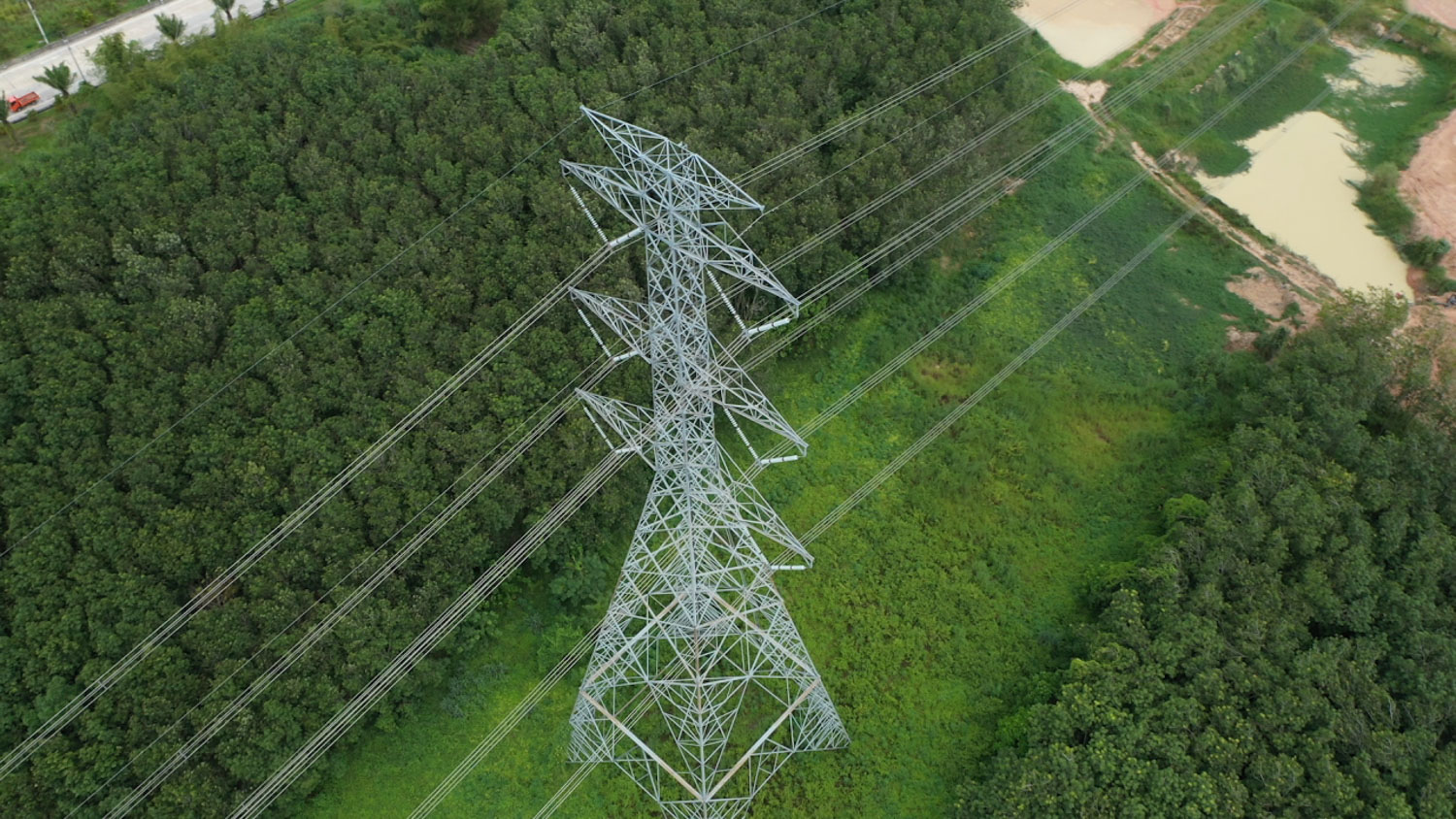 Tour hydroélectrique vue d’en haut entourée d’arbres. Une route se trouve à gauche.
